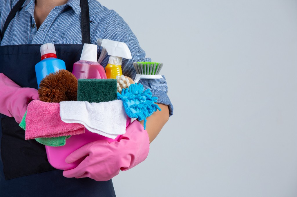 Professional cleaner holding bucket of supplies — space on the right for your headline